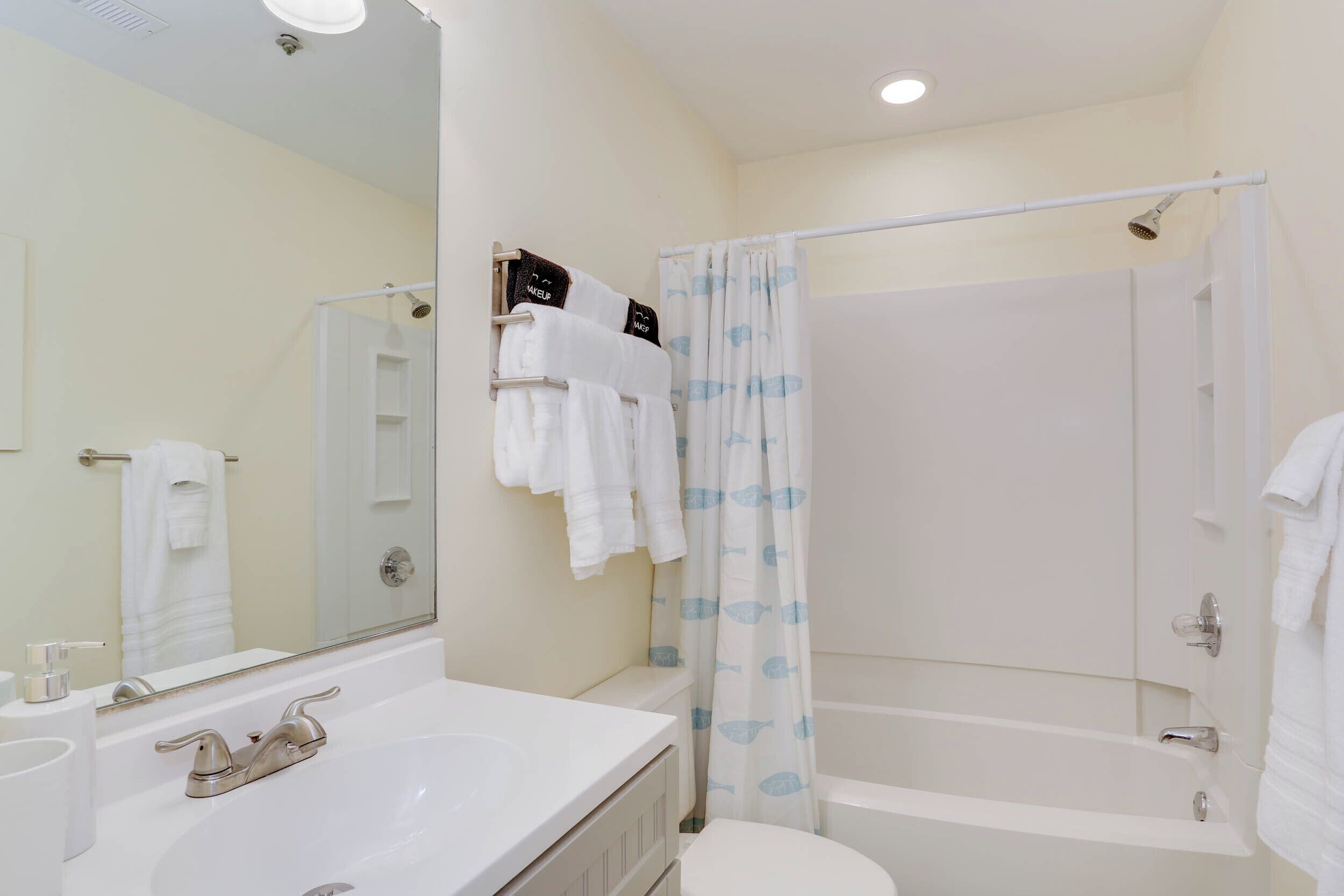 A bathroom with a white sink, mirror, and bathtub.