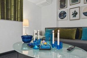 Un salon moderne avec une table basse en verre, des bougies décoratives et une télécommande.