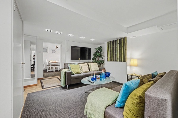 Inviting living space with generous seating and easy connection to the dining area. Please note lower ceiling sections typical of a basement apartment.