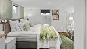 Une chambre moderne avec un lit, des lampes de chevet, un téléviseur et des œuvres d’art accrochées aux murs.