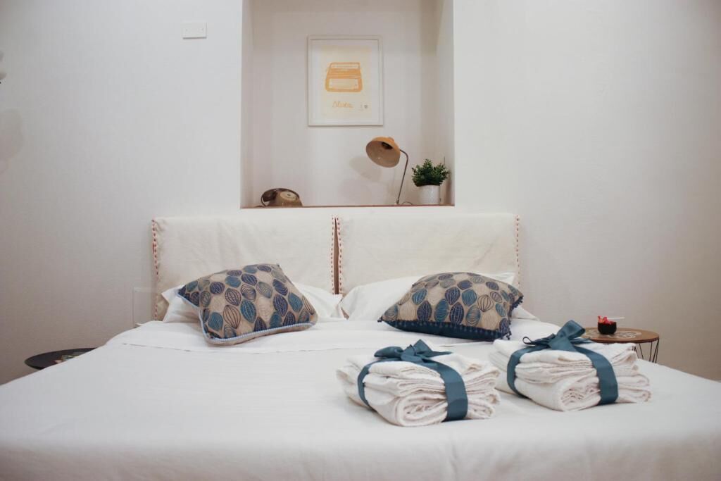 A neatly made bed with patterned pillows, a bedside table with a lamp, and a framed picture on the wall.