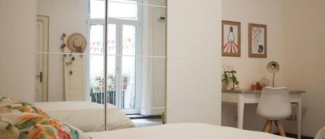 Un dormitorio con cama, escritorio y silla. Se ve una ventana con vistas al exterior.