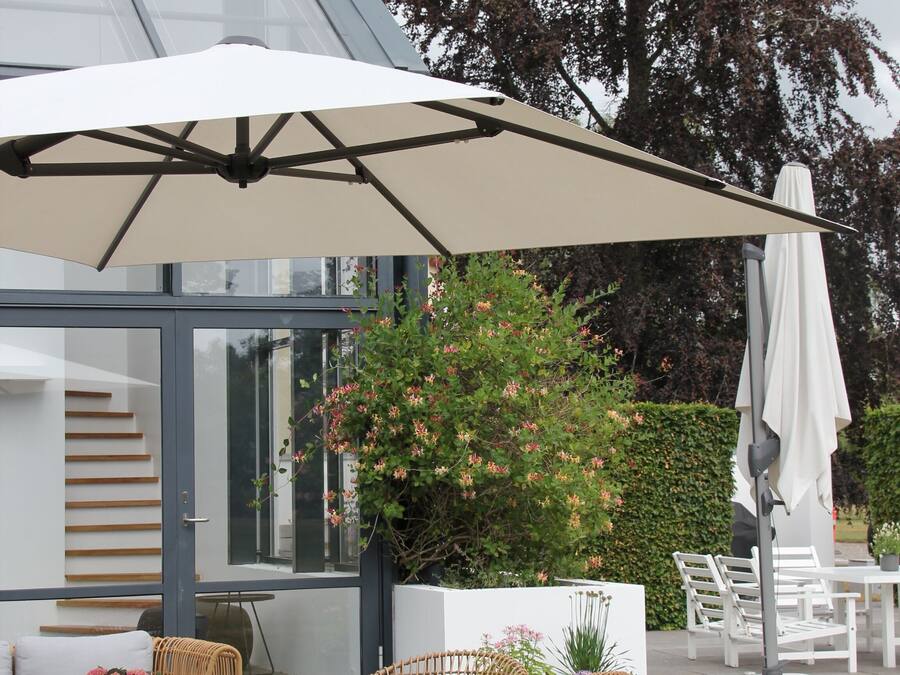 Et udendørs opholdsområde med fletningsmøbler, et bord og en stor parasol.