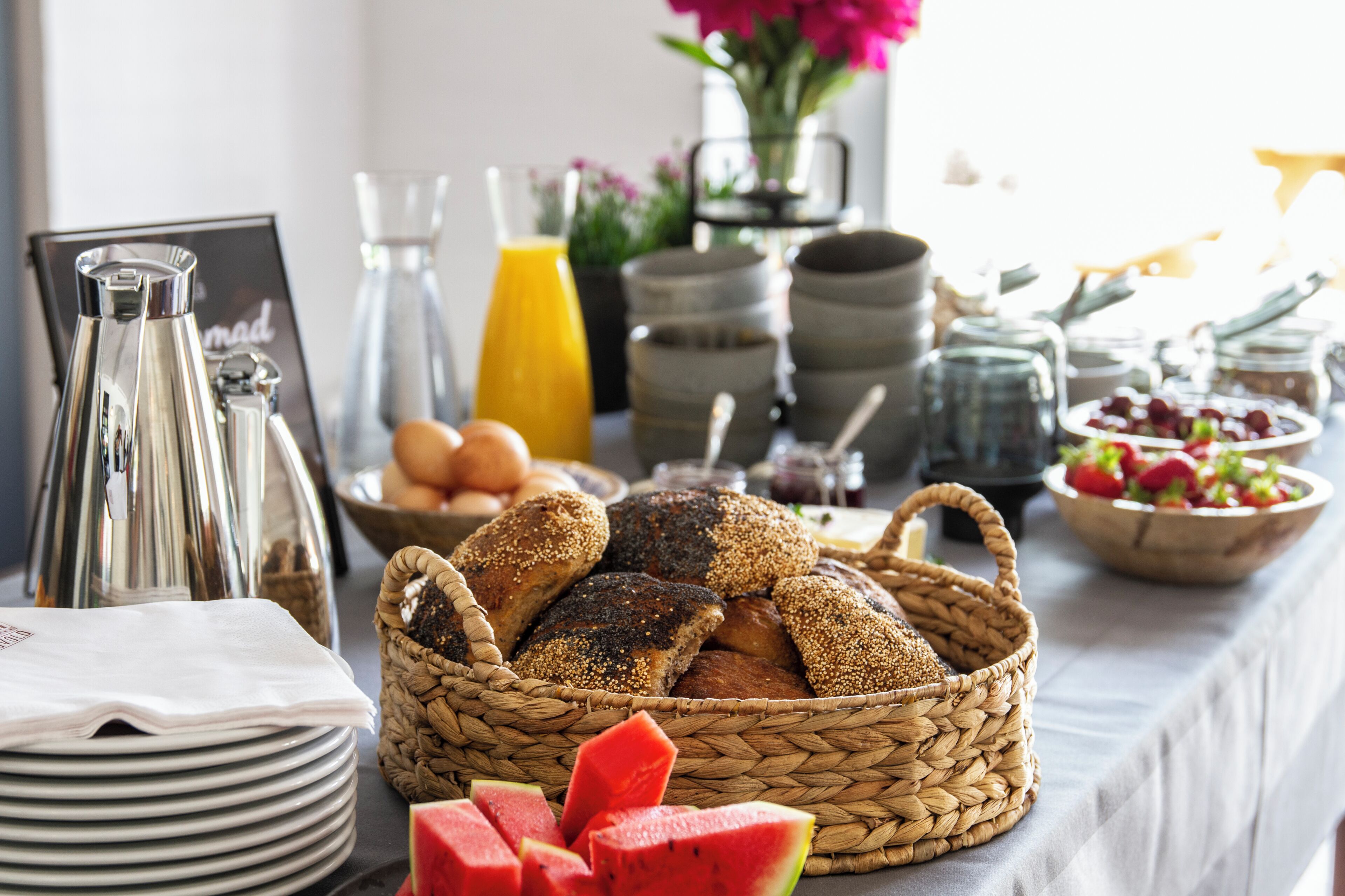 A breakfast buffet with bread, fruits, and beverages.