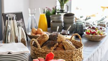 A breakfast buffet with bread, fruits, and beverages.