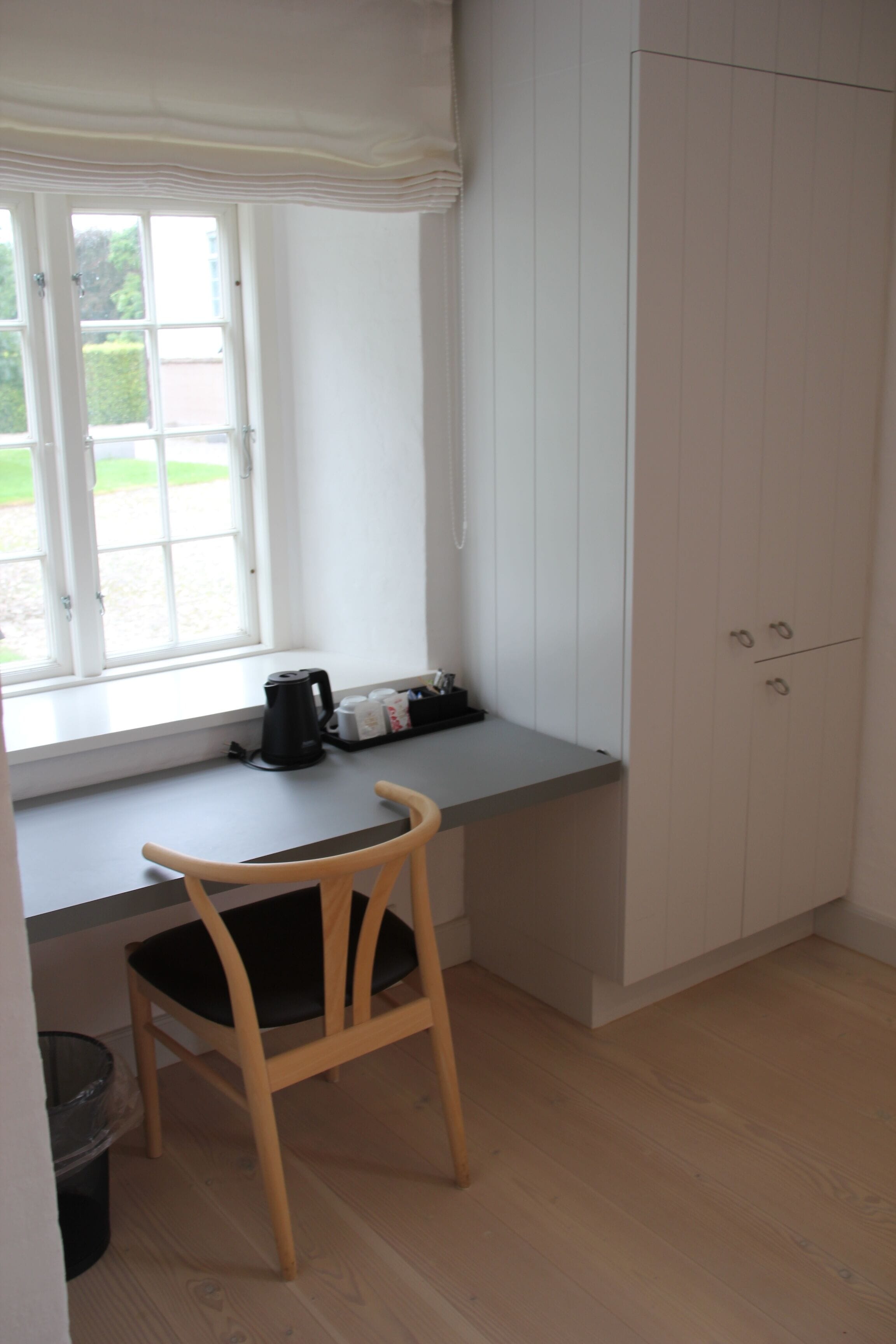 A small kitchenette with a window, a chair, and a cabinet.