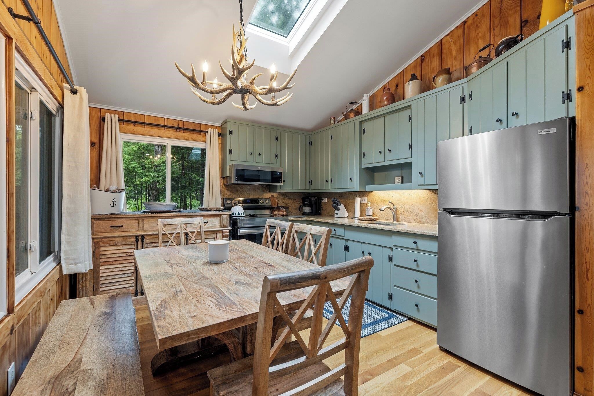 Een moderne keuken met houten kastjes, een roestvrijstalen koelkast en een houten eettafel.