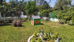 Um pequeno jardim com uma estrutura em forma de estufa, plantas em vasos e cerca branca.