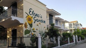 Um edifício com um mural de girassóis e o texto "Elena's Garden".