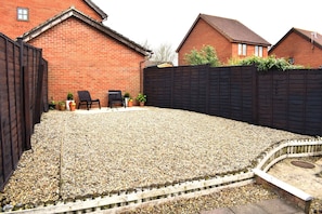 A backyard with a gravel surface, a wooden fence, and two chairs. - Host and Stay - The Rowton (Norwich)