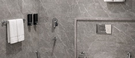 A modern bathroom with a marble shower, a toilet, and a bidet.