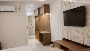 Une chambre d’hôtel moderne dotée d’un grand lit, d’un téléviseur fixé au mur, d’une coiffeuse en bois et d’un mur décoratif en marbre.