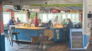 Un bar con barra, taburetes y un menú en la pizarra.
