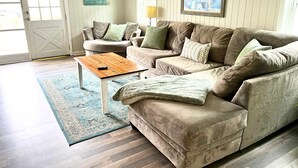 Una sala de estar con un sofá seccional marrón, una mesa de centro de madera y una alfombra azul estampada.