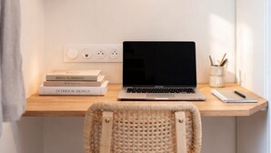 Een werkplek met een laptop, boeken en een rieten stoel.