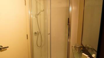 Un baño con cabina de ducha de vidrio, un lavabo blanco y un espejo.