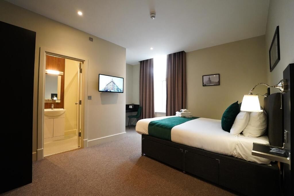 A hotel room with a bed, a desk, a TV, and a bathroom.