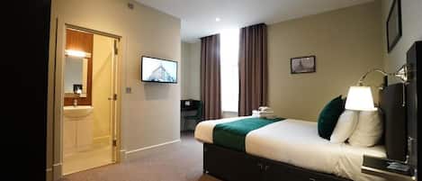 A hotel room with a bed, a desk, a TV, and a bathroom.