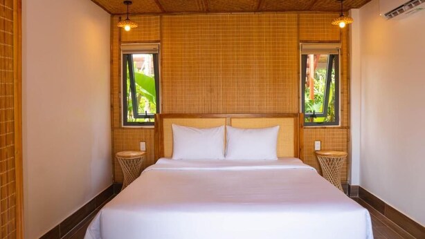 A bedroom with a large bed, two bedside tables, and a wooden ceiling. - FOREST HOME PHU QUOC (Phu Quoc)