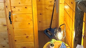 A wooden cabin interior with a sliding door, a broom, a lantern, and a small table with a plant. - Rustic Studio 4, Pets Welcome (Tennessee)