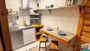 A compact kitchen with a microwave, toaster, and sink. There is a wooden stool and a small table with plates. - Rustic Studio 4, Pets Welcome (Tennessee)