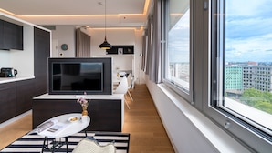 A modern apartment with a large TV, dining area, and a view of the city. - Vienna Residence, Philips Haus - Europlaza (Vienna)