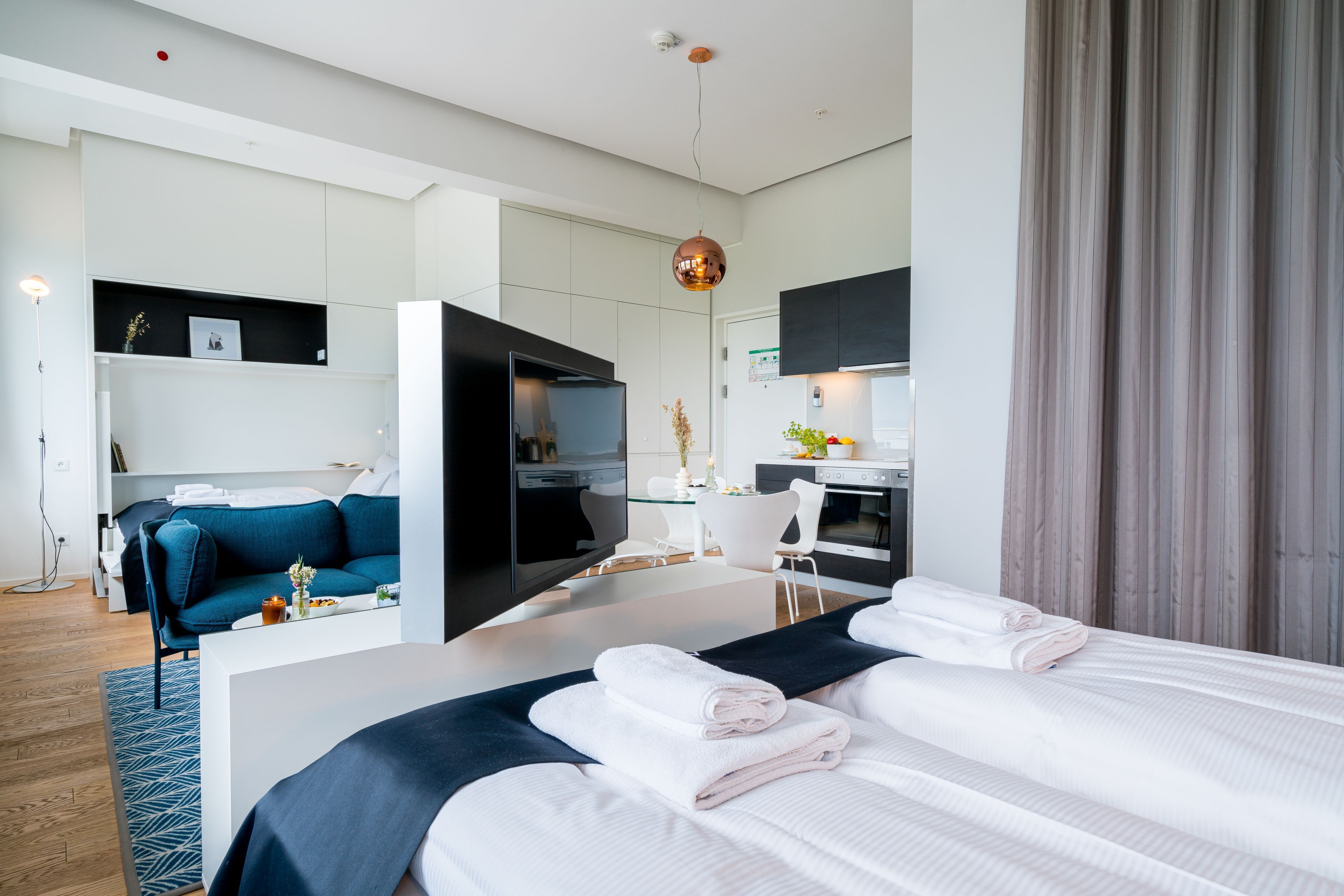 Una habitación de hotel moderna con una cama grande, un escritorio, un sofá y una kitchenette.