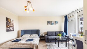 Moderni hotellihuone, jossa on sänky, sohva, työpöytä ja ruokailutila.