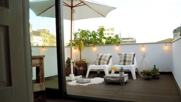 A rooftop terrace with a white umbrella, two white chairs, a small table, and potted plants. - Oporto Private Room/TERRACE (Porto)