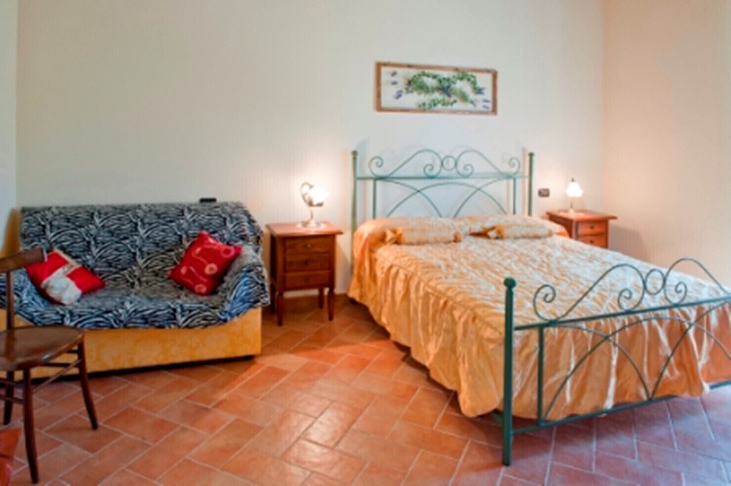 Ein Zimmer mit einem Bett, einem Schlafsofa, einem Nachttisch und einem an der Wand hängenden Bild.