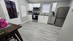 Una cucina moderna con mobili bianchi, un frigorifero in acciaio inossidabile e un forno a microonde.