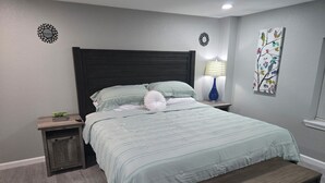 Una camera da letto con un letto, comodini, una panca e una parete con uno specchio decorativo e opere d'arte.