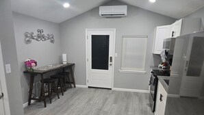 Una cucina con un piano di lavoro in legno scuro, una porta bianca e una finestra con persiane.