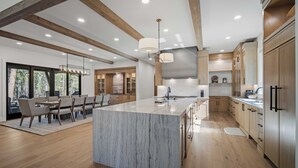 Una cocina moderna con una isla grande, vigas de madera y un comedor con sillas.