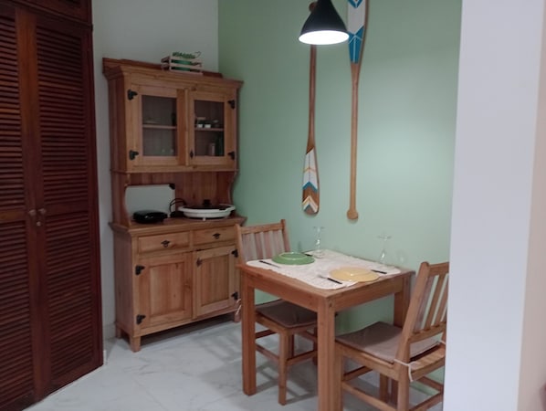 Ein Essbereich mit einem Holztisch und Stühlen, einem Schrank mit Glastüren und einer Pendelleuchte.