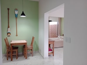 Ein Zimmer mit Esstisch, Stühlen, einem Bett und Blick auf eine Ziegelwand durch ein Fenster.