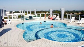 Una piscina en la azotea con sillones de descanso y vista panorámica de la ciudad.