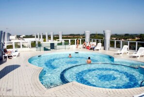 Ein Pool auf dem Dach mit Liegestühlen und Blick auf die Stadt.