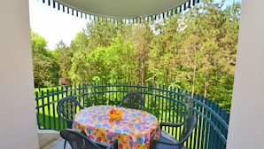 A round table with a floral tablecloth and four chairs, surrounded by a blue metal railing. - Comfortable Flat With Shared Pool (San Michele al Tagliamento)