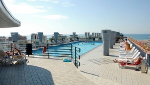A rooftop pool area with lounge chairs, a swimming pool, and a view of the sea. - Comfortable Flat With Shared Pool (San Michele al Tagliamento)