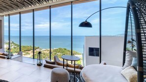 A modern living room with large windows, a black pendant lamp, and a view of the sea. - Sea View Beauty Excellent Location - Beach Front (Pattaya)