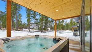 A hot tub in a covered outdoor area with a view of a snowy landscape and trees. - Newly Built, Spacious Duplex, Huge Garage, Hot Tub, Clubhouse Access! (Lead)