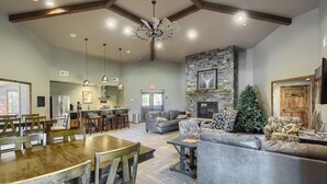 A spacious living area with a fireplace, a stone accent wall, and a cozy seating arrangement. - Newly Built, Spacious Duplex, Huge Garage, Hot Tub, Clubhouse Access! (Lead)