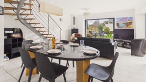Eine moderne Küche mit Wendeltreppe, einem Essbereich mit rundem Tisch und einem großen Fenster mit Blick ins Freie.
