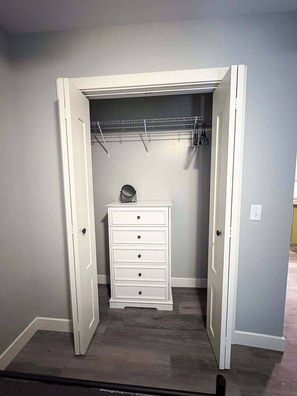 Ein begehbarer Kleiderschrank mit weißem Schminktisch und Kleiderstange.