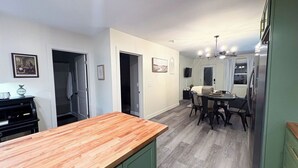 A kitchen with a wooden countertop, green cabinets, a dining area with a table and chairs, and a refrigerator. - Sage & Cedar
Cozy home ready for your stay (Webb City)