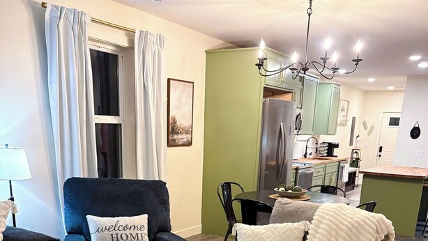 A living room with a sofa, a coffee table, and a dining area with a table and chairs. - Sage & Cedar
Cozy home ready for your stay (Webb City)