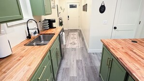 A kitchen with green cabinets, a wooden countertop, and a gray floor. - Sage & Cedar
Cozy home ready for your stay (Webb City)