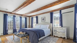 A bedroom with a large bed, wooden beams, a white dresser, and a window with curtains. - Spacious Farmhouse Near the Beach Circa 1860 (Biddeford)