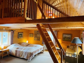 A cabin with a loft bedroom, a staircase, and a cozy sitting area. - 7 Person Holiday Home in Lekeryd (Lekeryd)